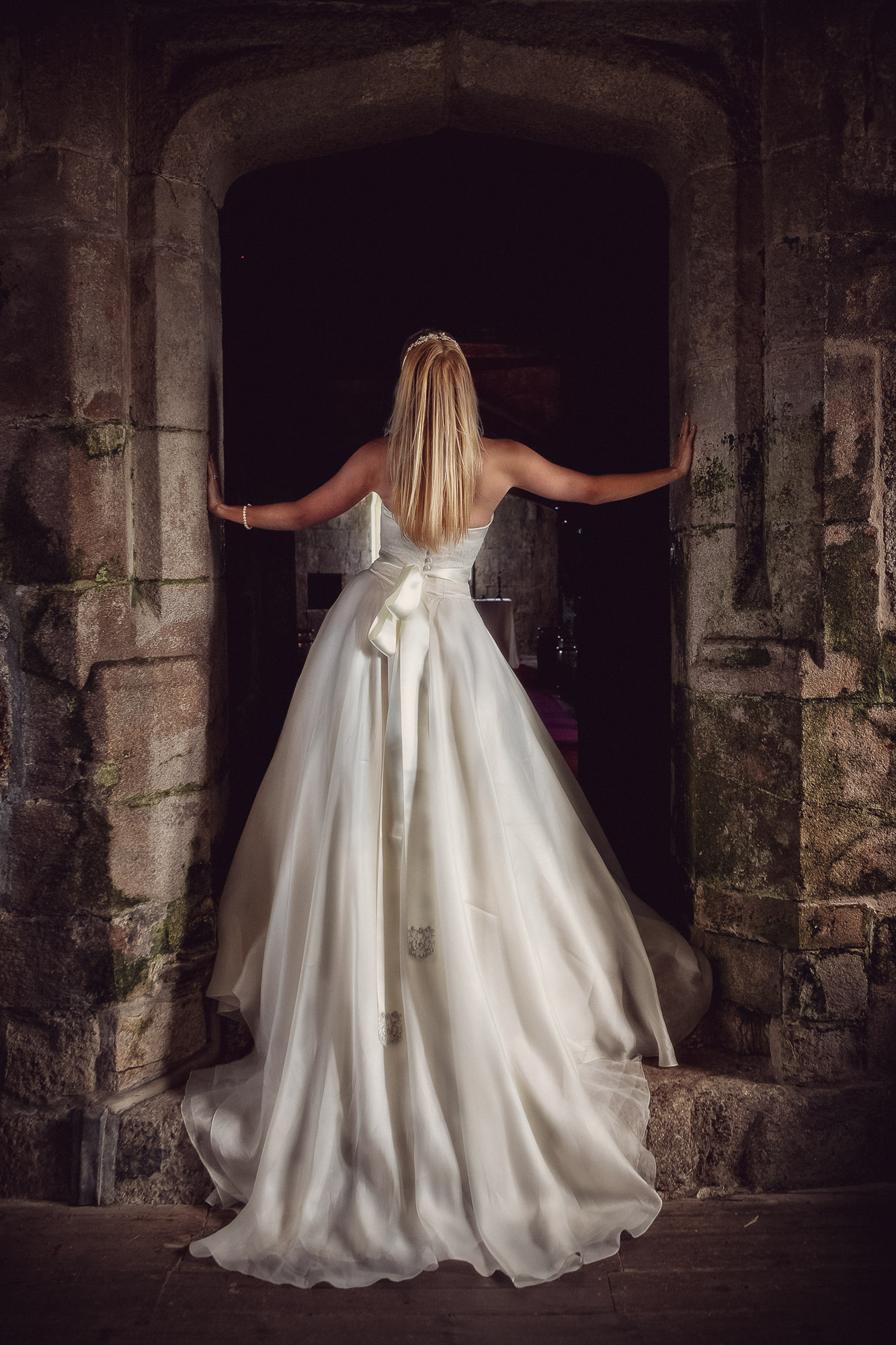 Devon wedding photography by Ember Weddings, bride framed in a stone archway